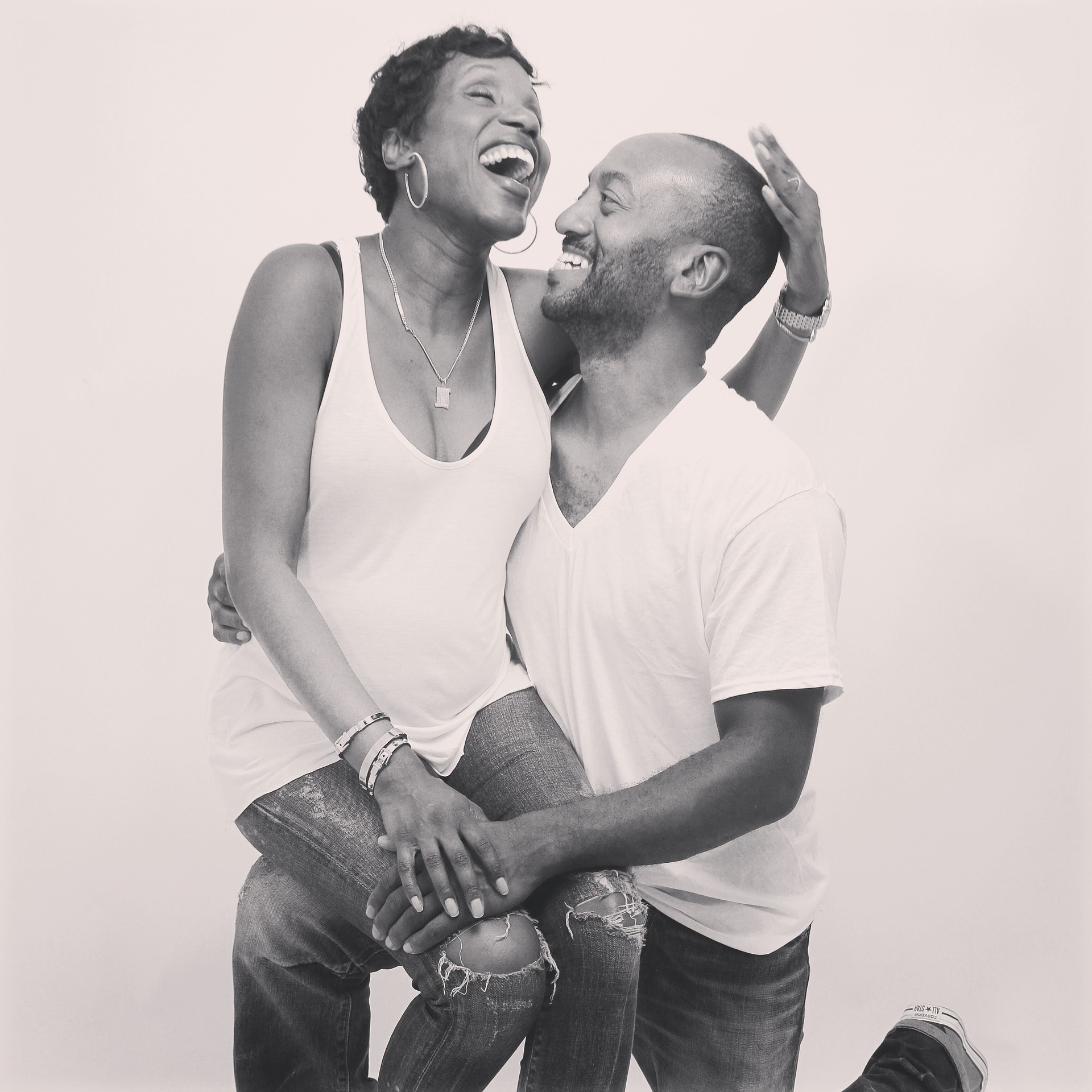 Laughing couple embracing in casual white shirts