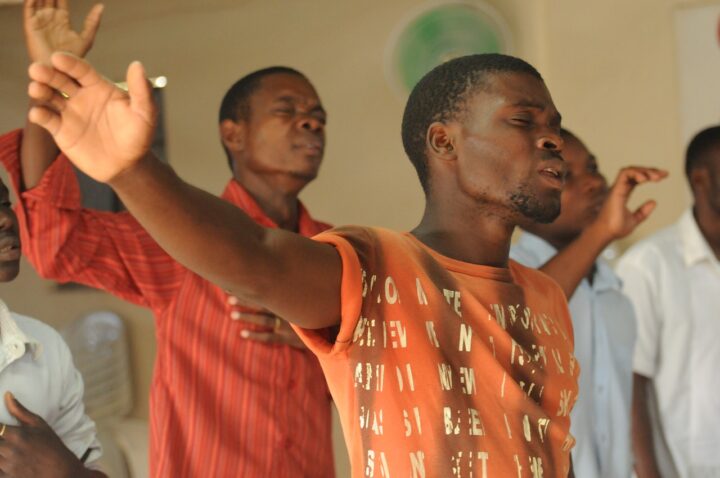 People with raised hands and closed eyes