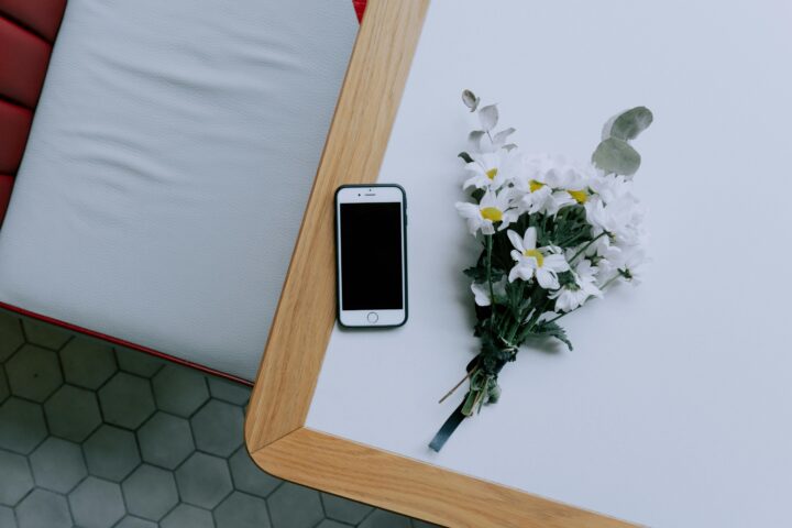 Smartphone and white daisy bouquet on table